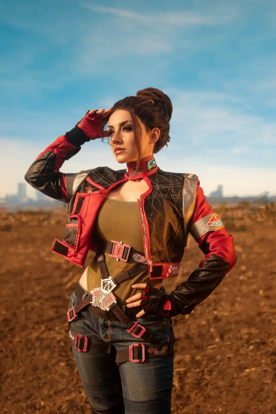 Ezy in a red-and-black jacket cosplay with her hair up, in a desert landscape